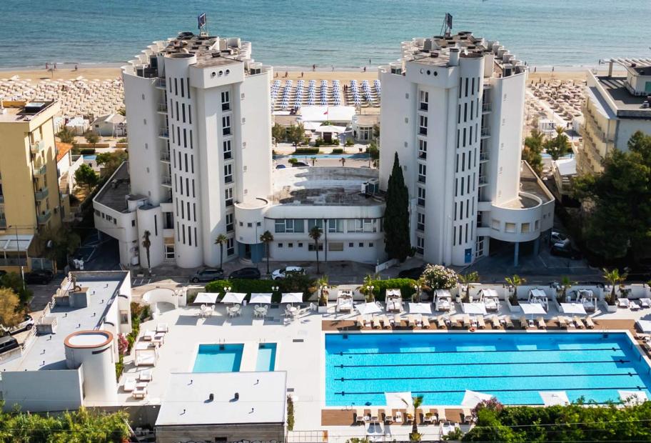 Hotel moderno con piscine blu e spiaggia dorata, atmosfera di relax e lusso.
